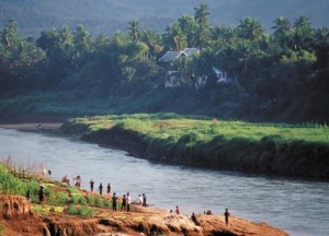 LAO farmers tend vegetable terraces on the Nam Khan River near Luang Prabang. Improved rice production allows farmers to diversify their crops, and therefore their diet and income—but life throughout Lao PDR, seen in the surrounding photo, continues to depend on rice. (Photo: Peter Fredenburg)