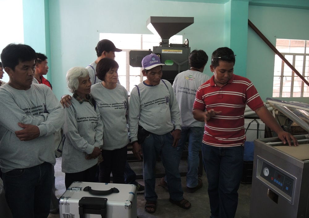 Engr. Sandro (in red) orients members of MPHRFAC on the use of the vacuum sealer to improve the packaging of heirloom rice. (Photo: IRRI)